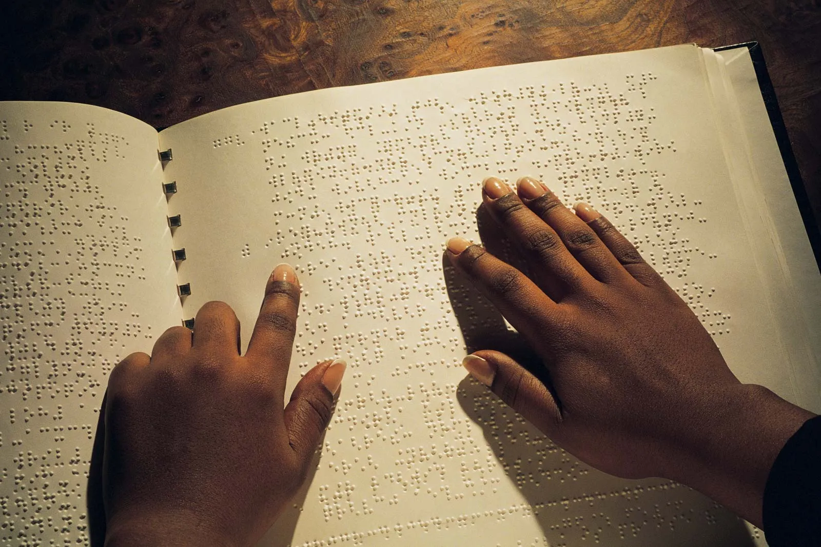 Hands reading a book written in braille.